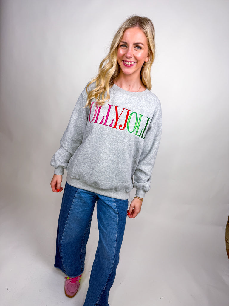 Woman wearing gray Holly Jolly sweatshirt with pink, red, and green holiday lettering