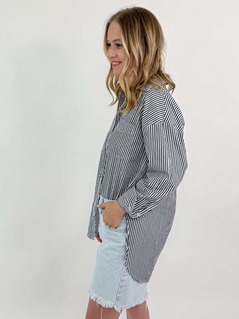 Woman wearing a grey and white vertical striped oversized button-down shirt