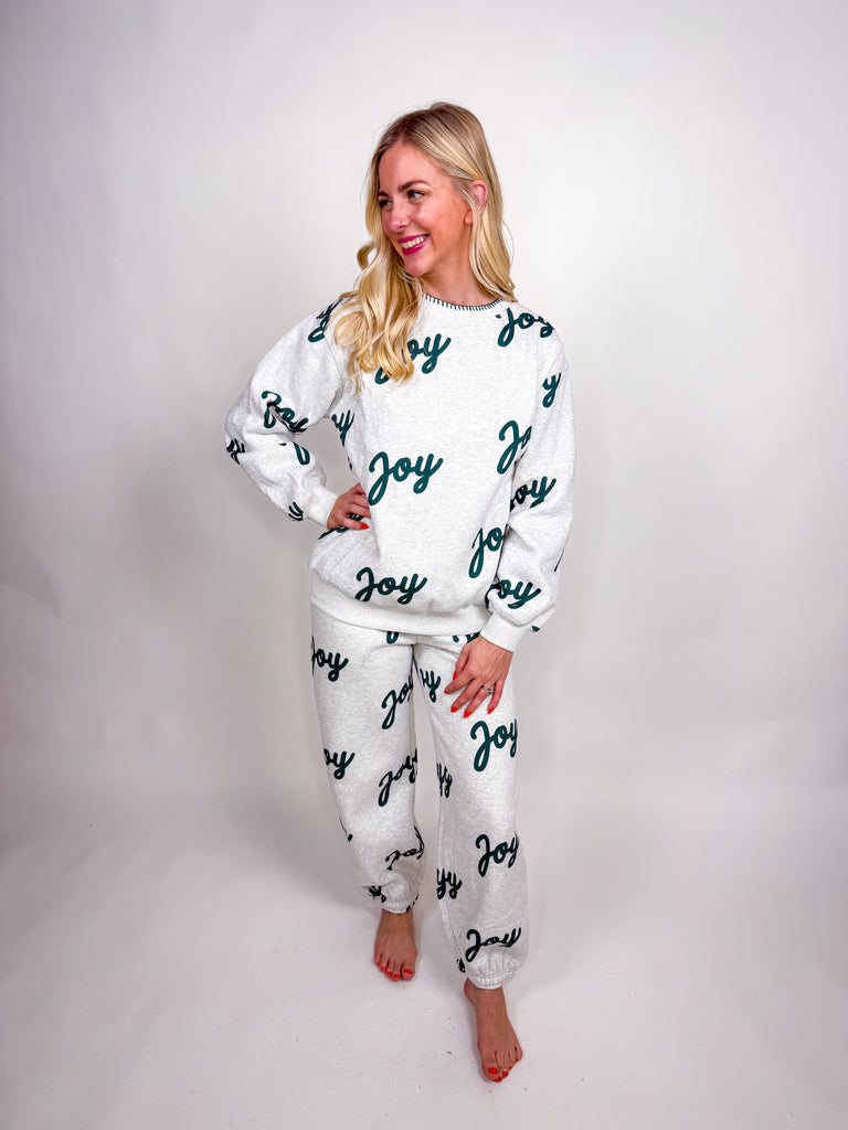 Woman wearing gray lounge set with green Joy lettering all over