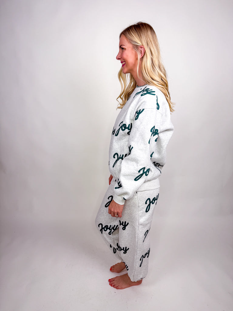 Woman wearing gray lounge set with green Joy lettering all over