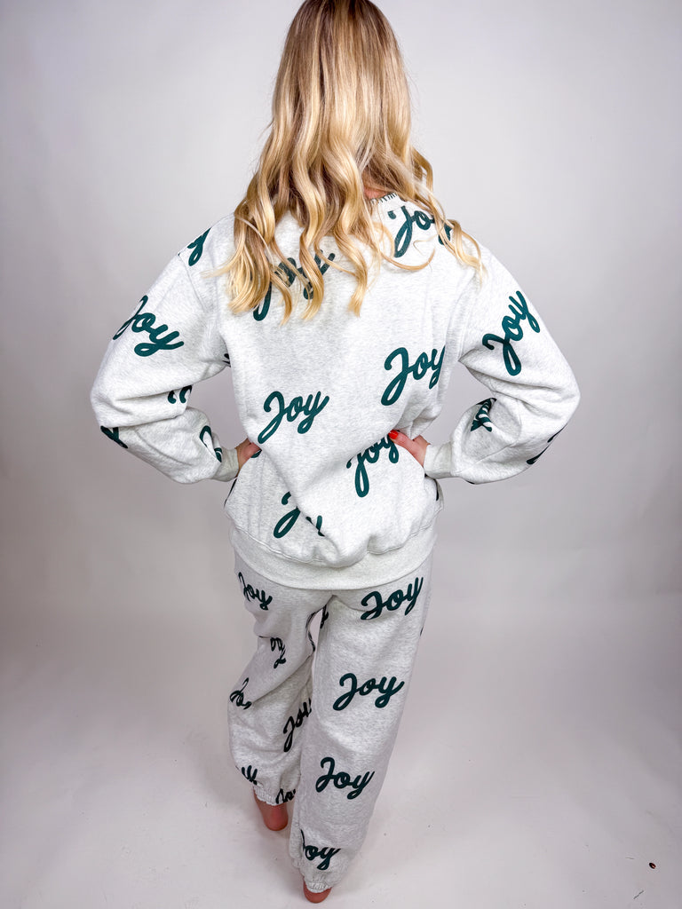 Woman wearing gray lounge set with green Joy lettering all over