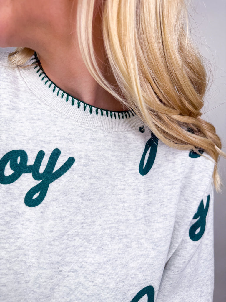 Woman wearing gray lounge set with green Joy lettering all over