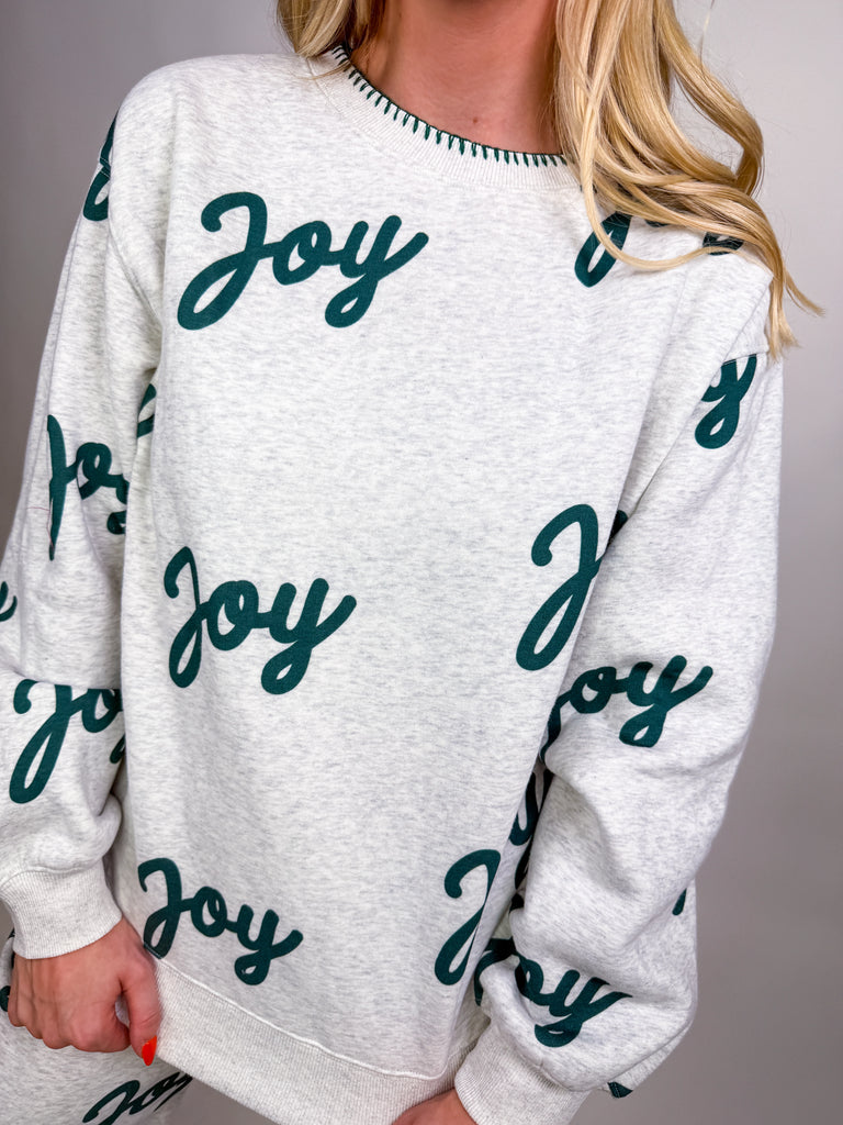 Woman wearing gray lounge set with green Joy lettering all over