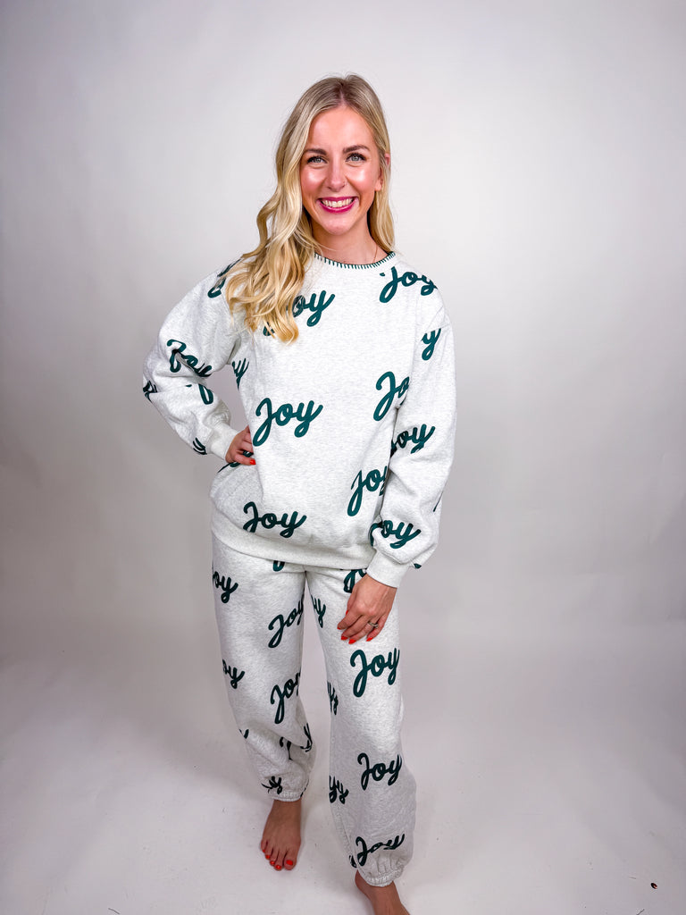 Woman wearing gray lounge set with green Joy lettering all over