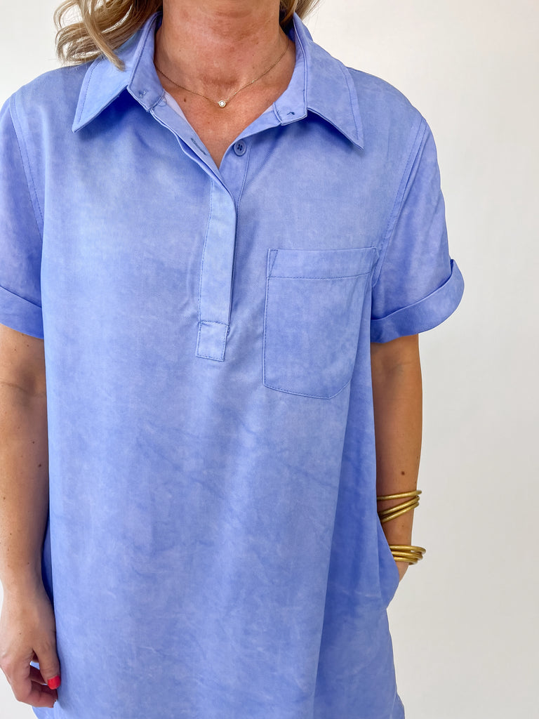 Woman wearing a casual blue polo dress with short cuffed sleeves and collar