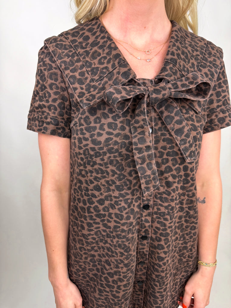 model wearing brown leopard print mini dress with bow neckline and button-front detail