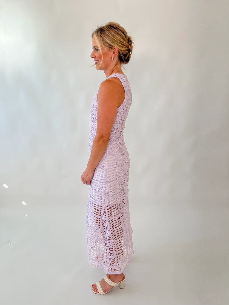 Model wearing sleeveless lavender lace midi dress with floral embroidery and sheer hemline