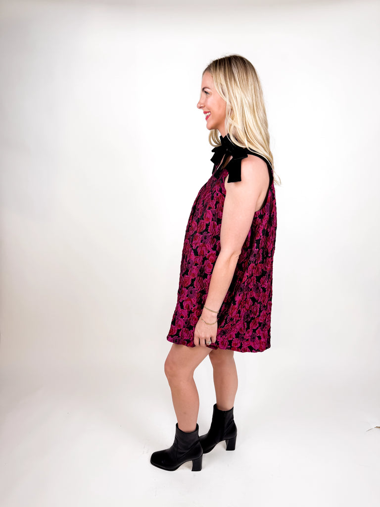 model wearing magenta floral jacquard mini dress with black velvet bow straps