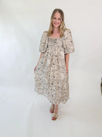 Woman wearing a neutral floral puff sleeve midi dress with an open tie-back design