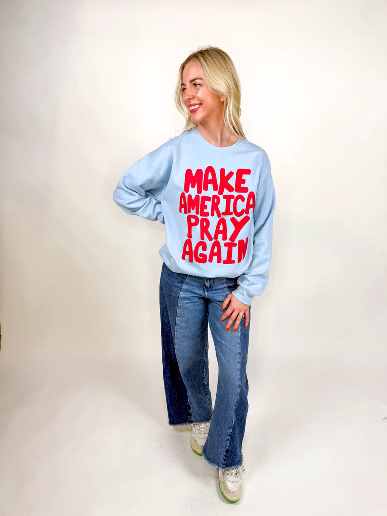 model wearing light blue sweatshirt with red “Make America Pray Again” lettering