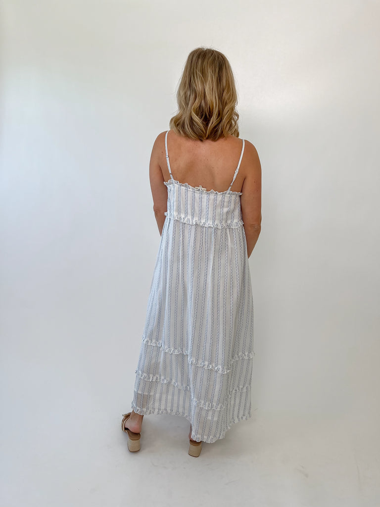 Woman wearing a blue and white striped ruffle maxi dress with adjustable straps