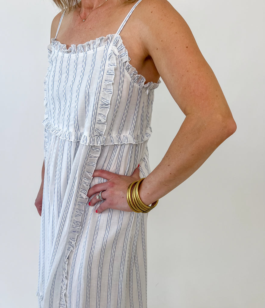 Woman wearing a blue and white striped ruffle maxi dress with adjustable straps