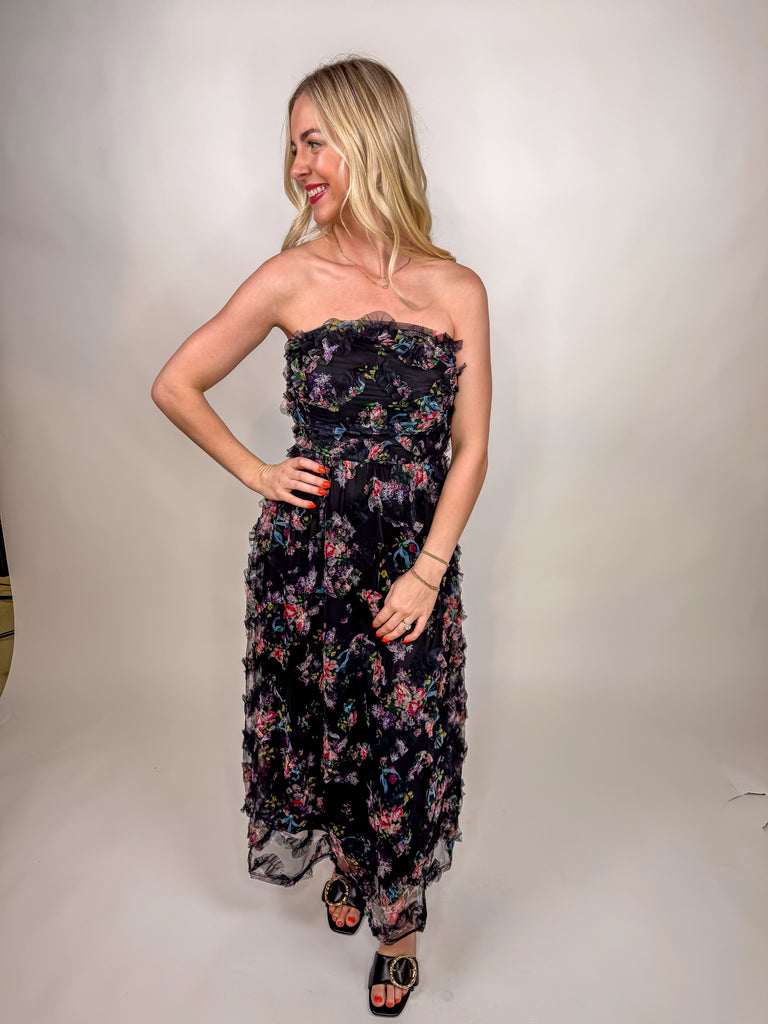 model wearing black strapless floral chiffon midi dress with ruffle details