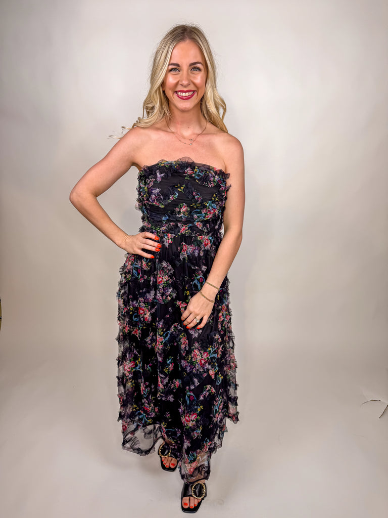 model wearing black strapless floral chiffon midi dress with ruffle details