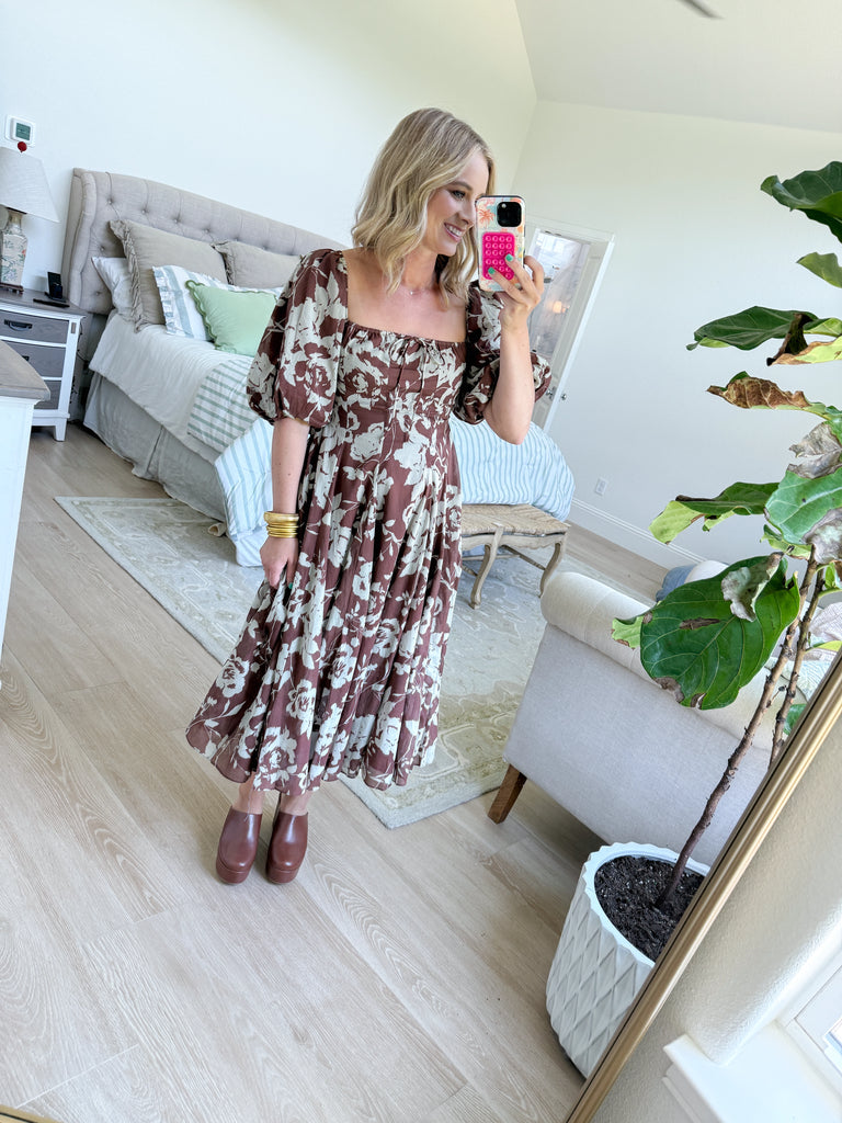 Woman wearing mocha brown puff-sleeve midi dress with cream floral print, square neckline, fitted bodice, and flowy skirt