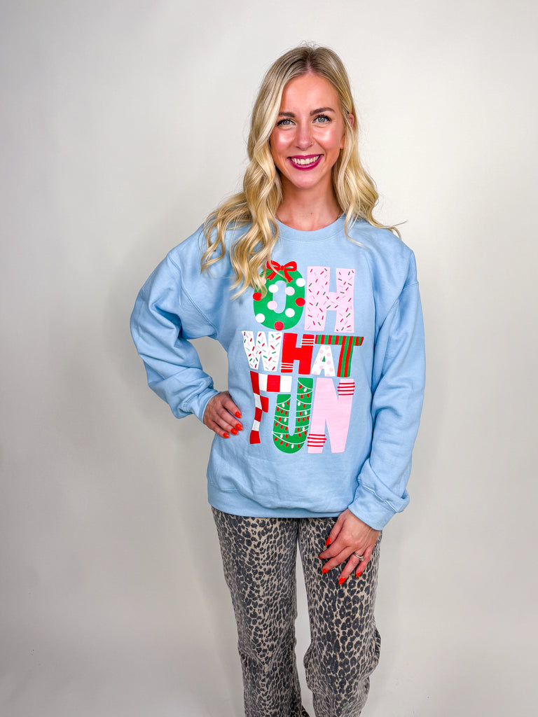 Woman wearing light blue Oh What Fun sweatshirt with red, pink, and green Christmas lettering