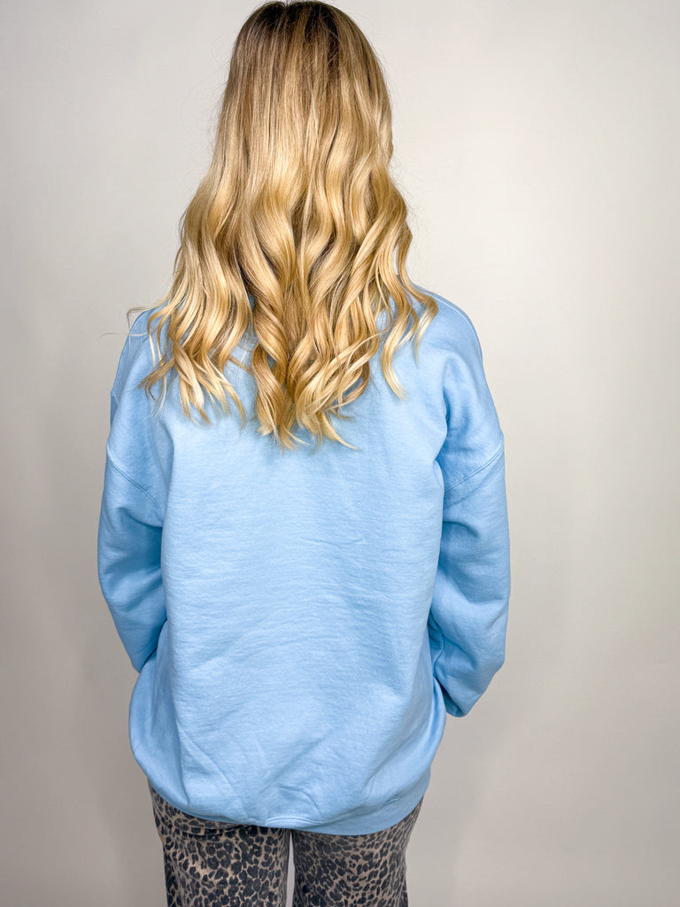 Woman wearing light blue Oh What Fun sweatshirt with red, pink, and green Christmas lettering