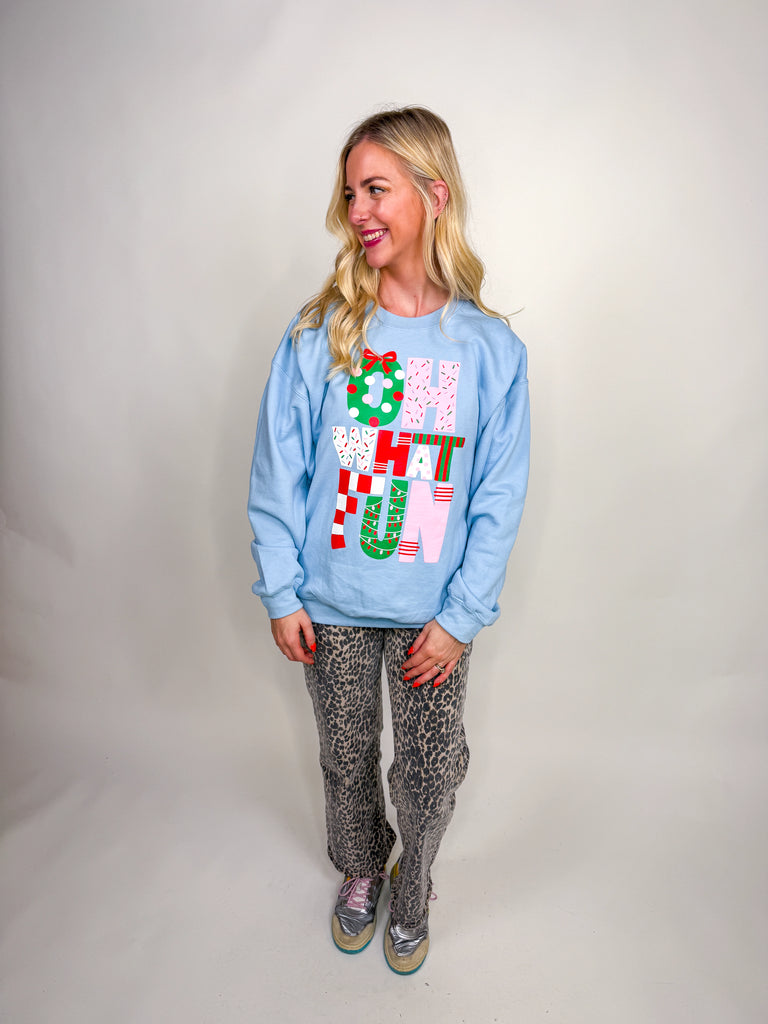 Woman wearing light blue Oh What Fun sweatshirt with red, pink, and green Christmas lettering