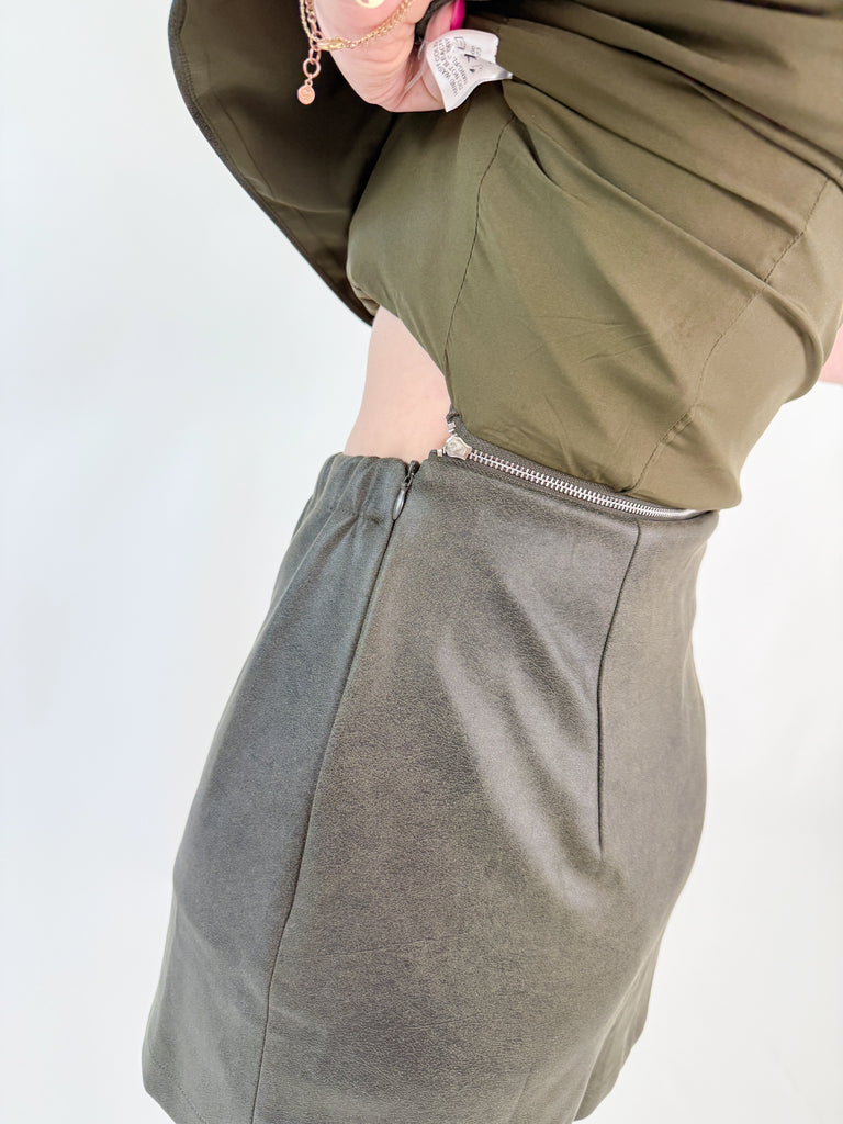 Woman wearing an olive 3-in-1 romper dress with button front and mini skirt overlay