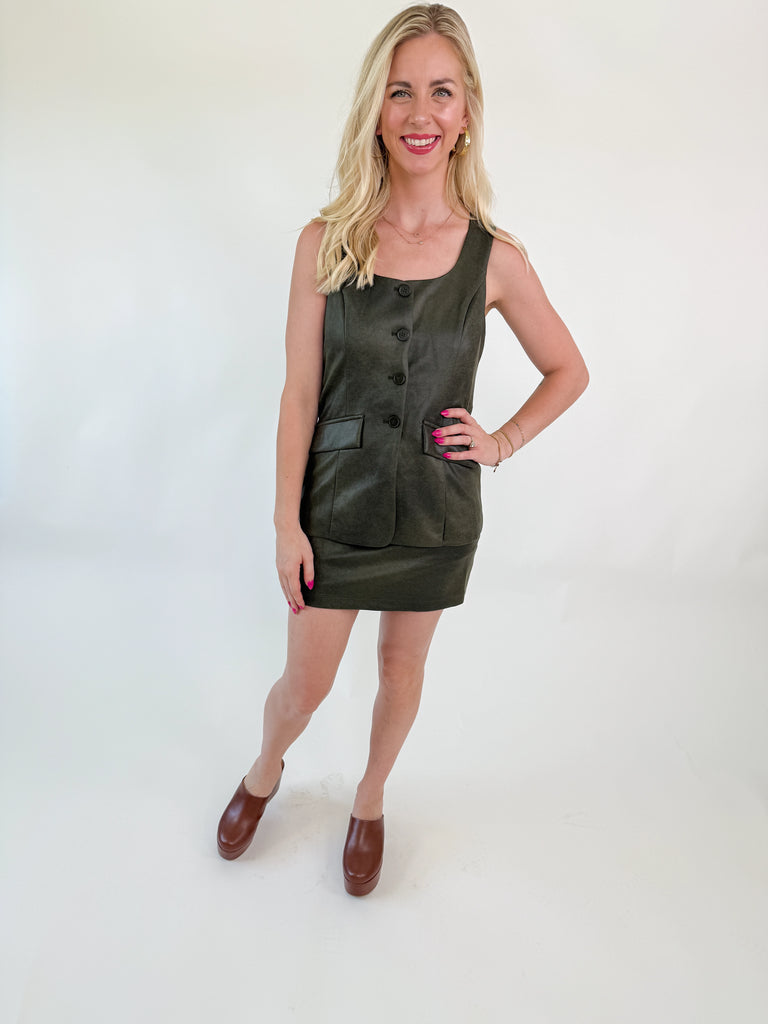 Woman wearing an olive 3-in-1 romper dress with button front and mini skirt overlay
