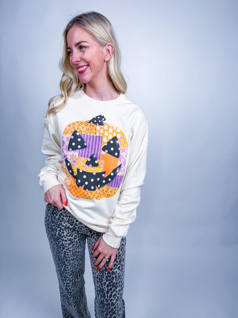 Woman wearing cream sweatshirt with colorful patchwork pumpkin Halloween design