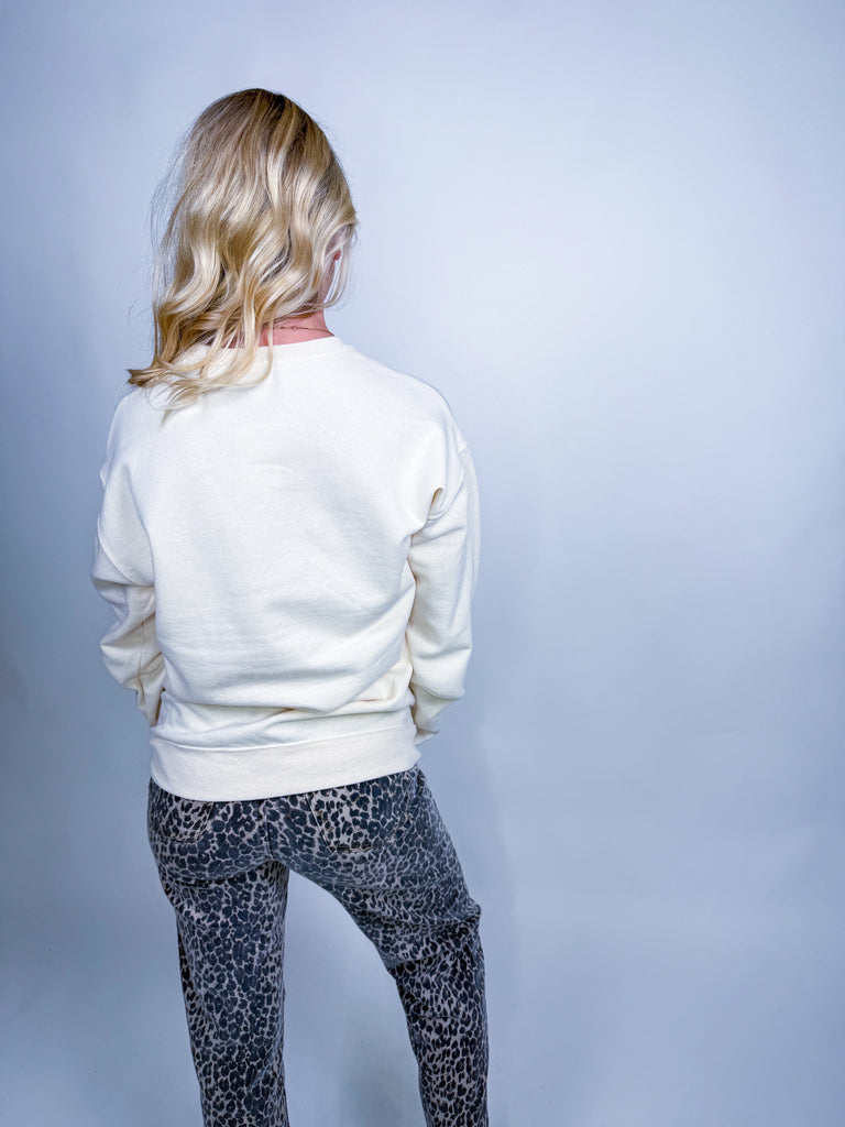 Woman wearing cream sweatshirt with colorful patchwork pumpkin Halloween design