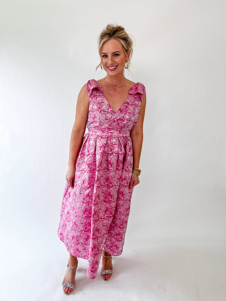 Woman wearing a pink rosette textured v-neck midi dress with ruffle straps