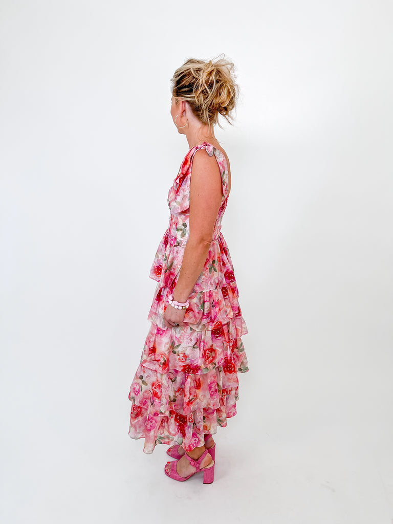 Woman in pink floral maxi dress with ruffle tiers and tie straps