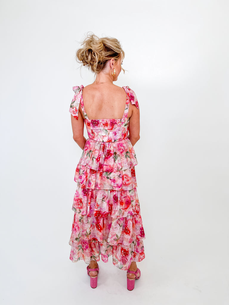 Woman in pink floral maxi dress with ruffle tiers and tie straps