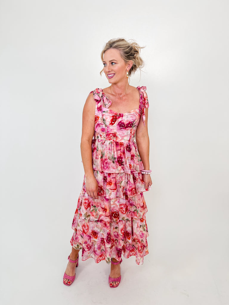 Woman in pink floral maxi dress with ruffle tiers and tie straps