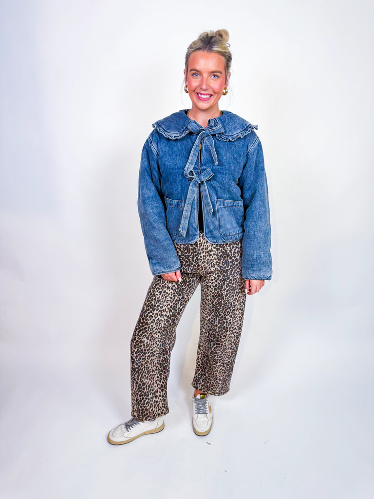 Woman wearing denim puffer jacket with ruffle collar and bow front ties