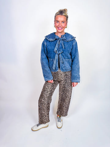 Woman wearing denim puffer jacket with ruffle collar and bow front ties