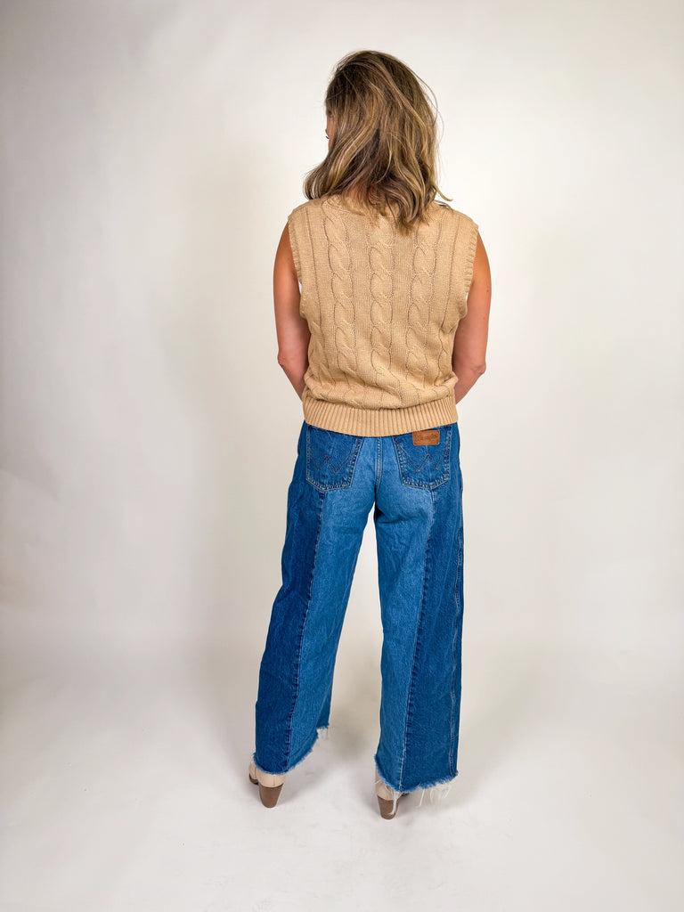 Woman wearing a camel cable knit vest with embroidered horseshoes and a deep V-neckline