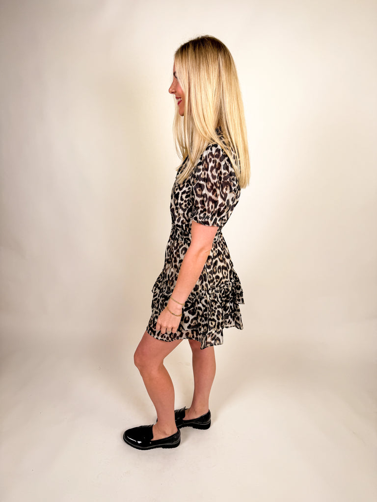 Woman wearing a leopard-print ruffle mini dress with puff sleeves, tie neckline, and tiered hem