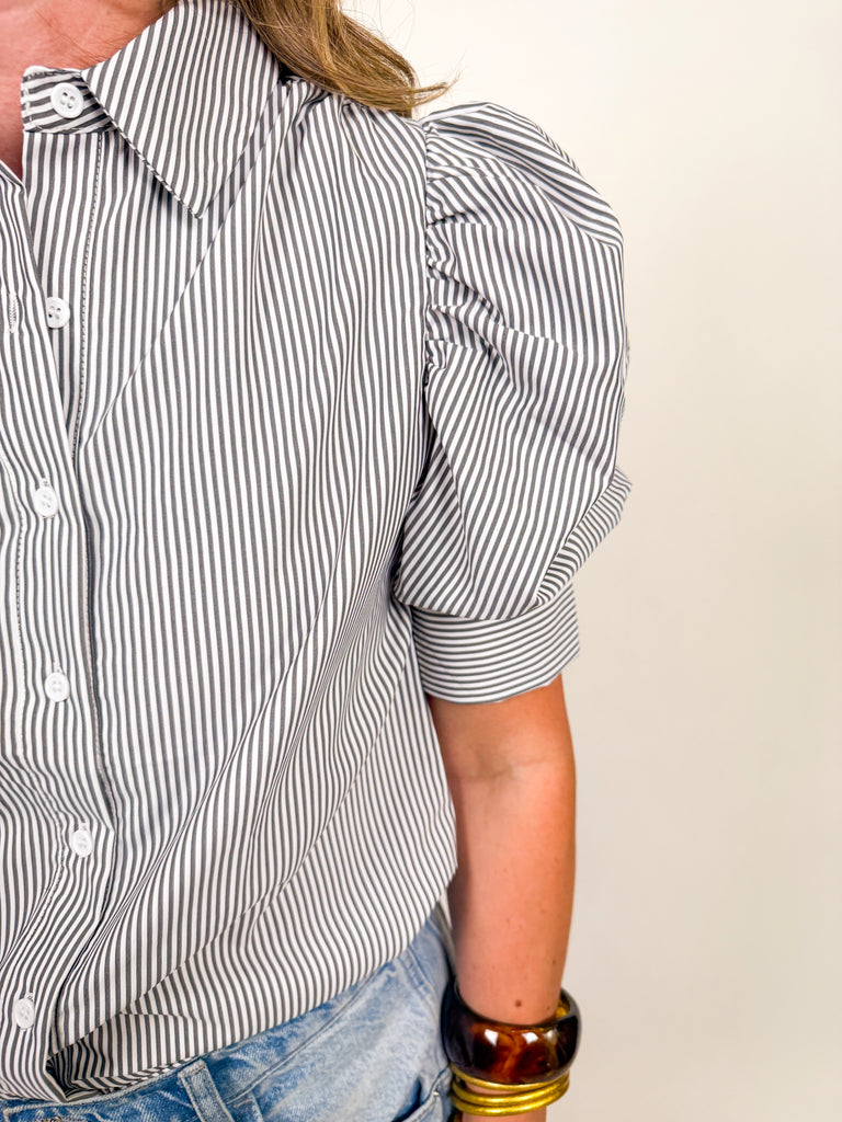 Woman wearing a black and white striped puff-sleeve blouse with button front