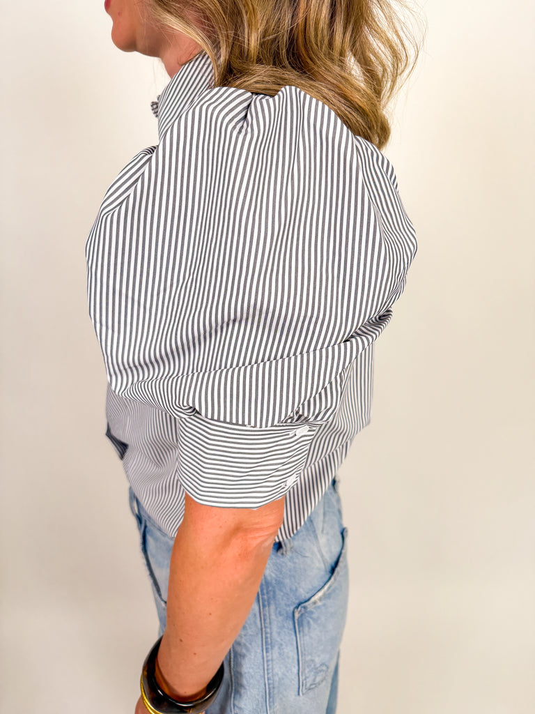 Woman wearing a black and white striped puff-sleeve blouse with button front
