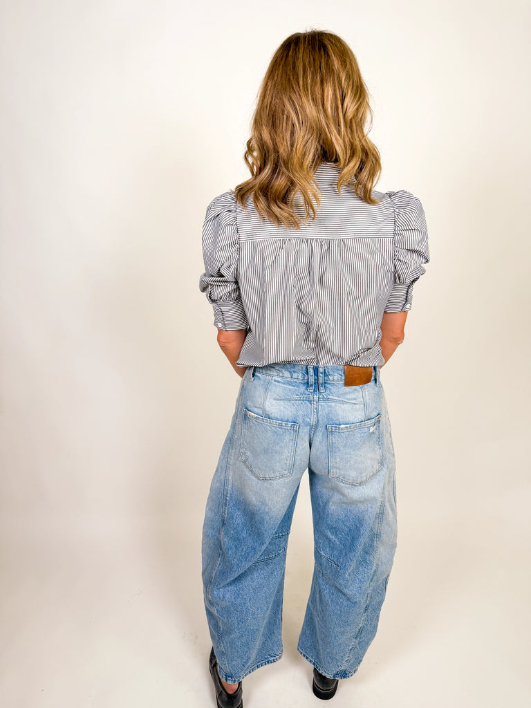Woman wearing a black and white striped puff-sleeve blouse with button front