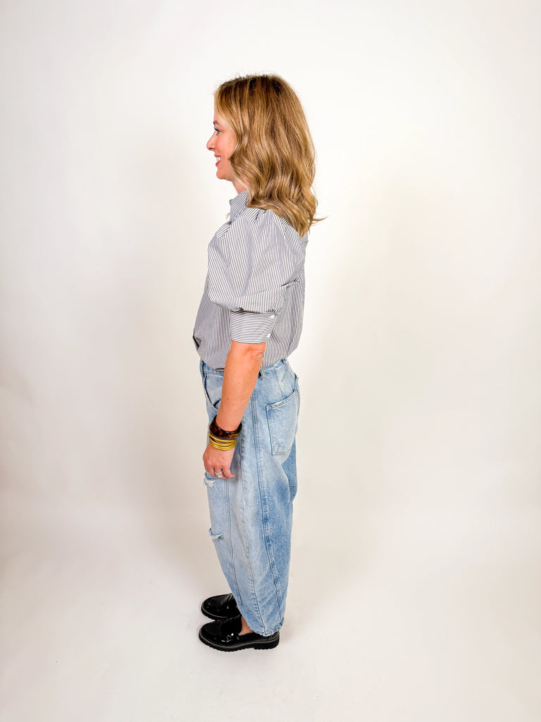 Woman wearing a black and white striped puff-sleeve blouse with button front