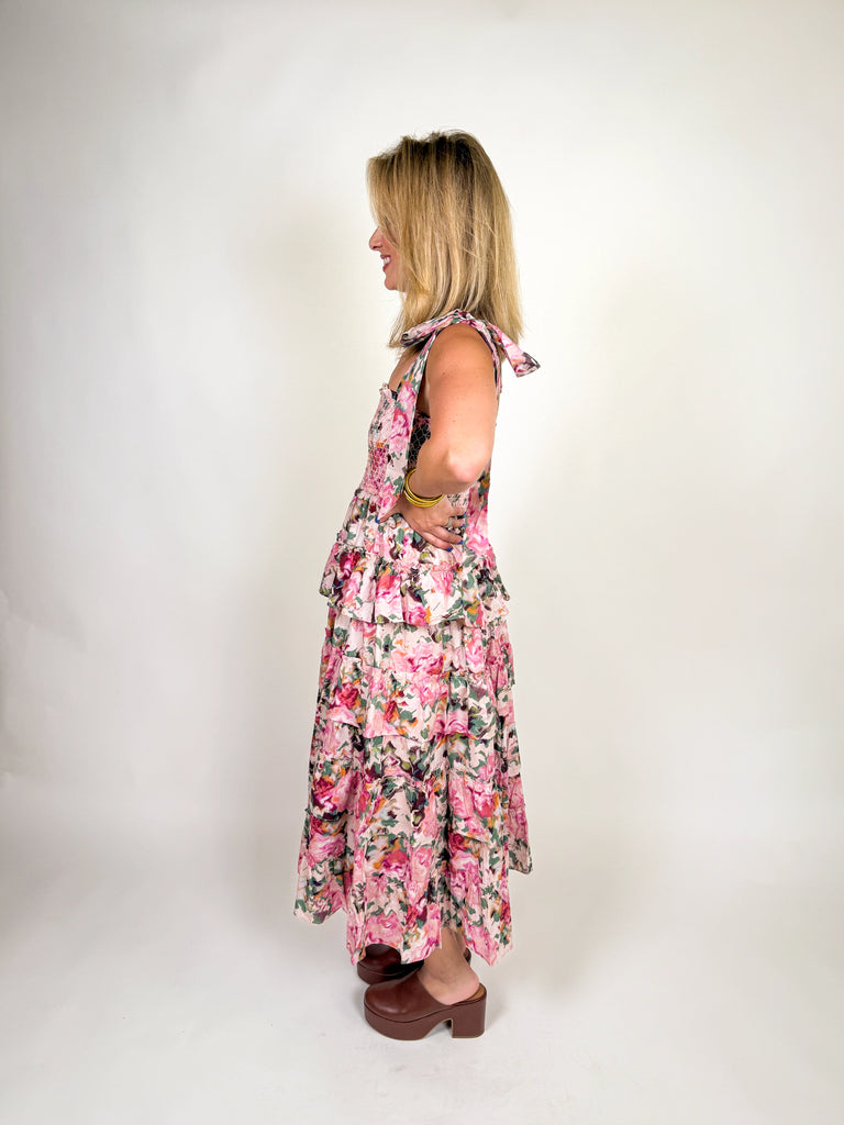 Woman wearing a tiered pink floral smocked maxi dress with tie straps and ruffle details