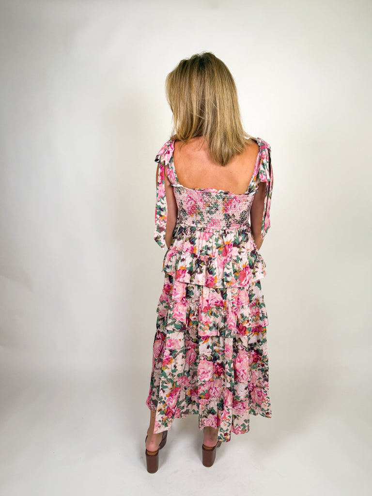 Woman wearing a tiered pink floral smocked maxi dress with tie straps and ruffle details