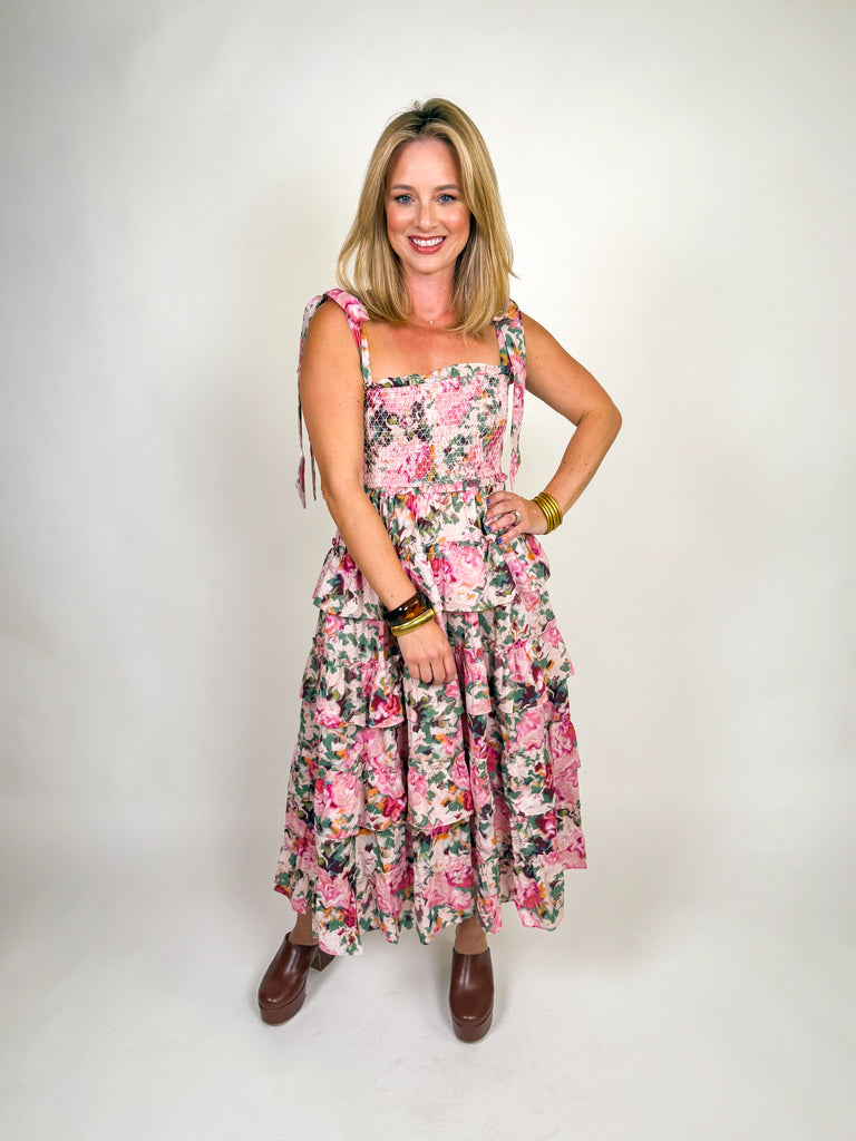 Woman wearing a tiered pink floral smocked maxi dress with tie straps and ruffle details