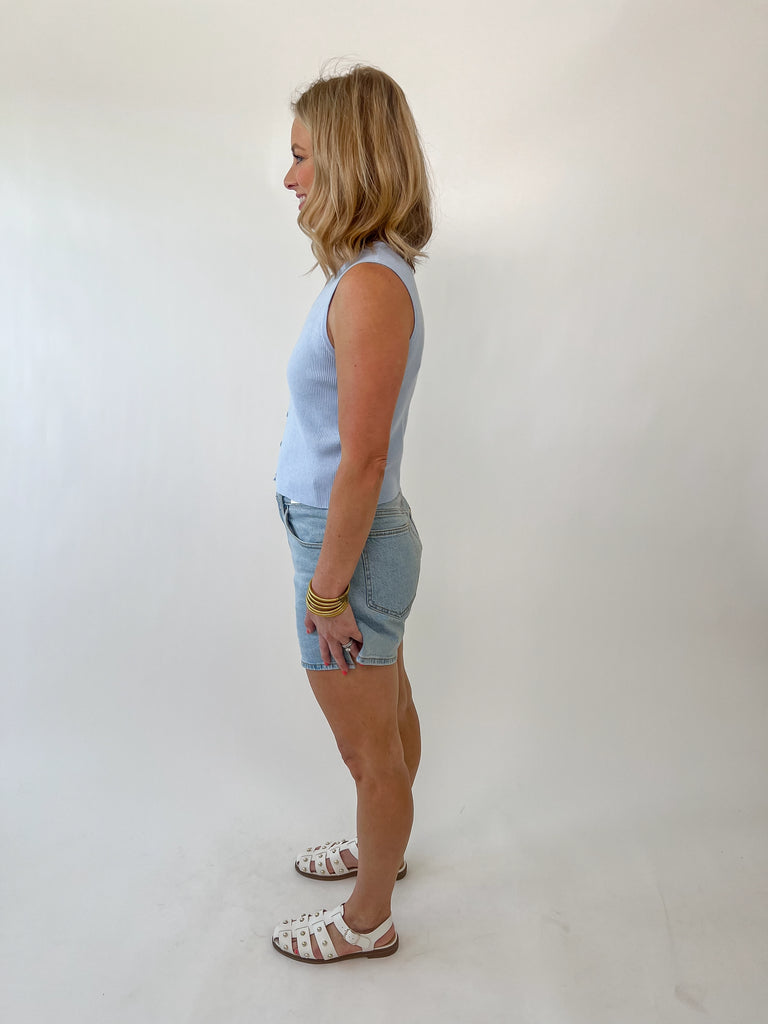 Woman wearing a sleeveless light blue knit button-front tank