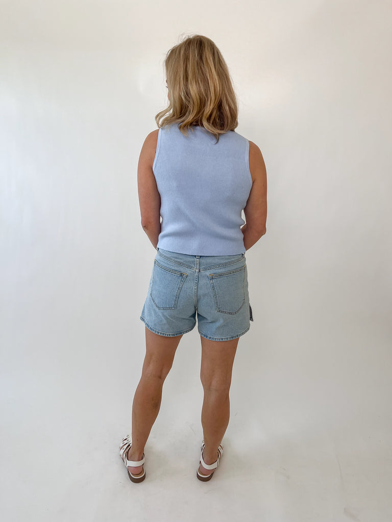 Woman wearing a sleeveless light blue knit button-front tank