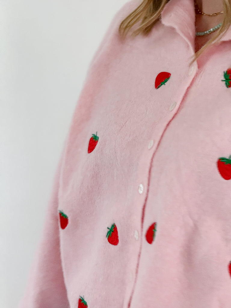 Pink knit sweater top with embroidered strawberries and button-up front
