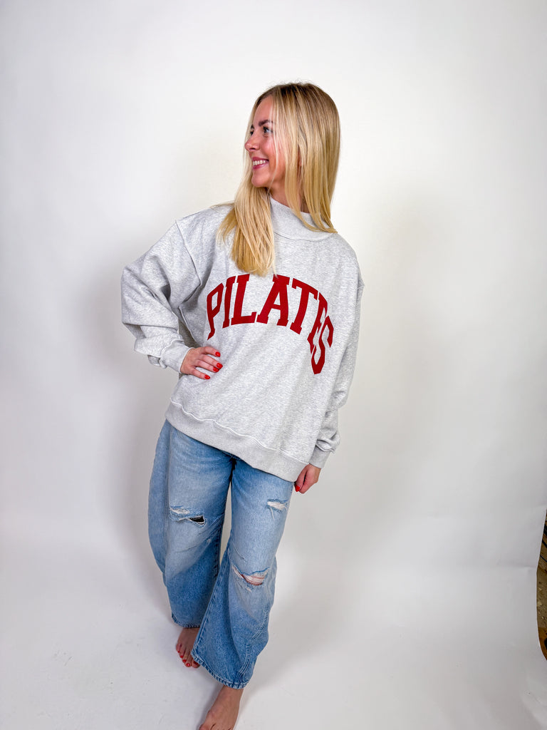 Woman wearing a reversible sweatshirt with Pilates on one side and Yoga on the other