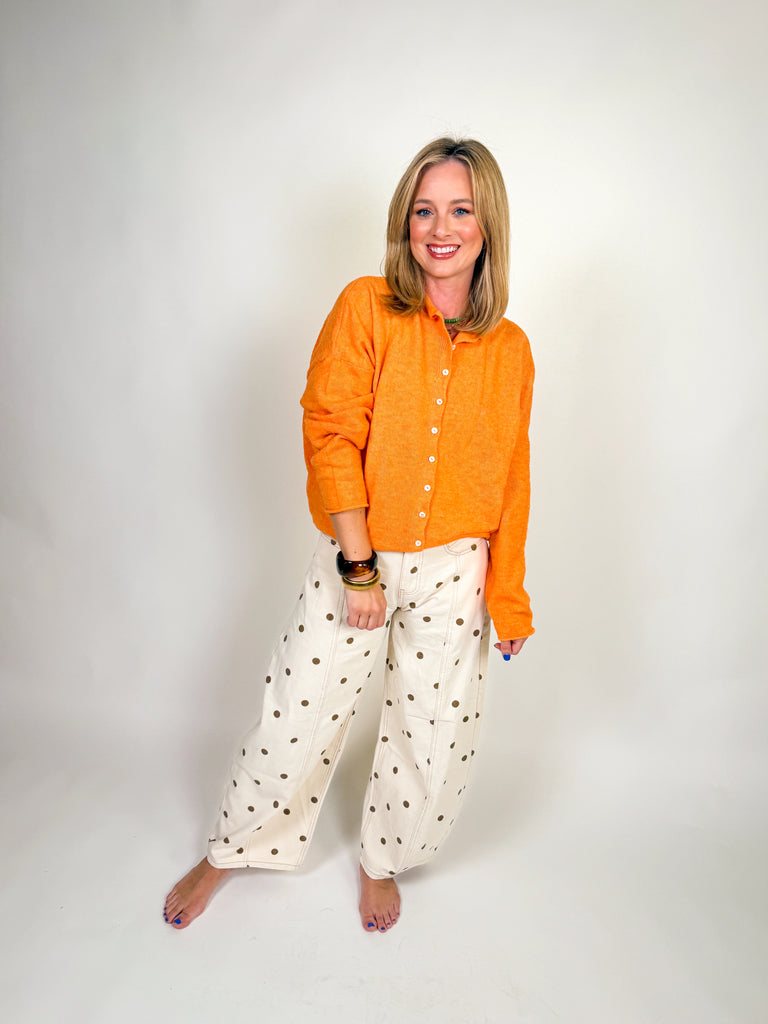 Woman wearing a bright orange button-down knit sweater with long sleeves and a slightly cropped hem
