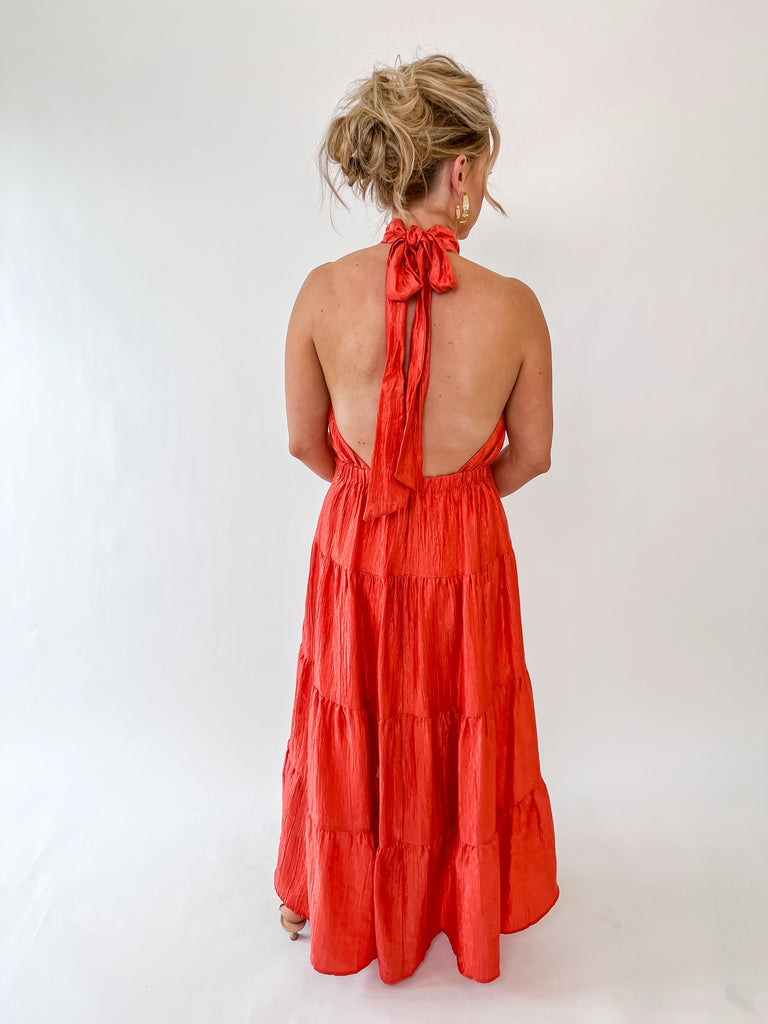 Vibrant orange halter maxi dress with tie-back detail and tiered skirt – perfect for weddings, parties, and summer events