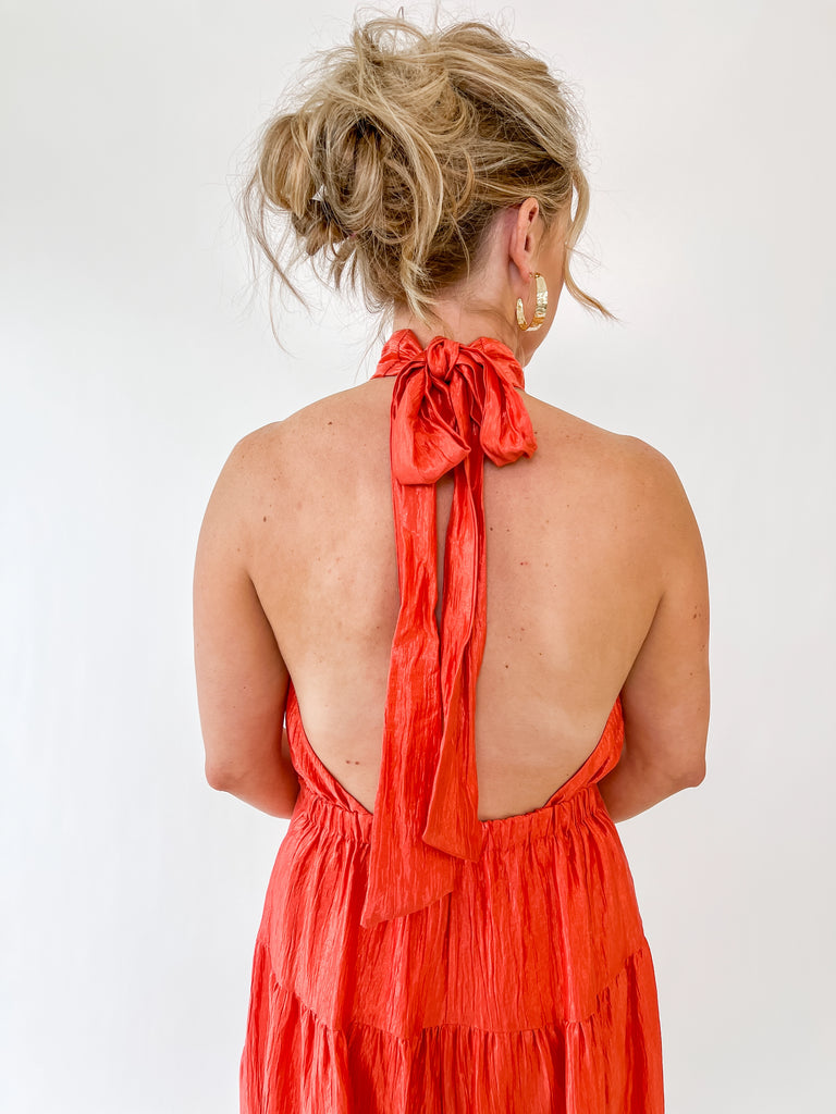 Vibrant orange halter maxi dress with tie-back detail and tiered skirt – perfect for weddings, parties, and summer events
