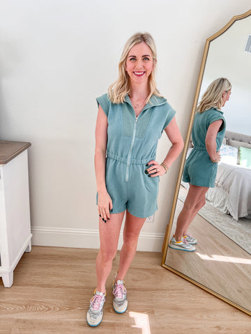 Light blue textured zip-up romper with a cinched waist and cap sleeves, styled with sneakers for a casual look