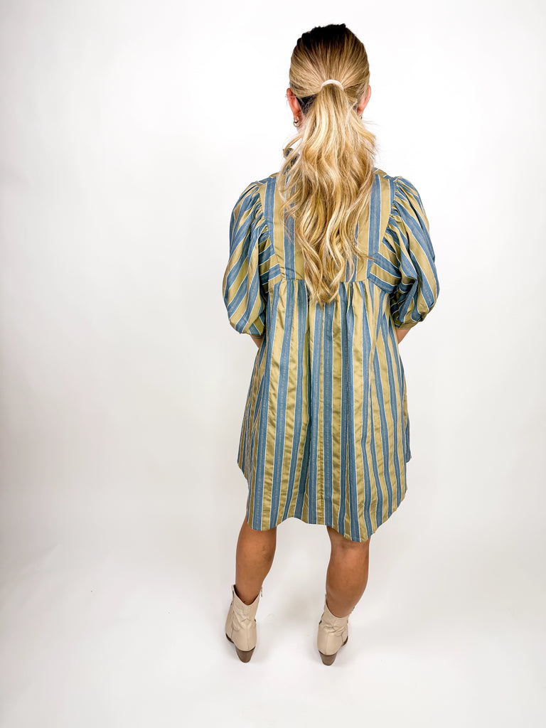The Marlowe Stripe Dress featuring blue and camel vertical stripes with a ruffled neckline and puff sleeves